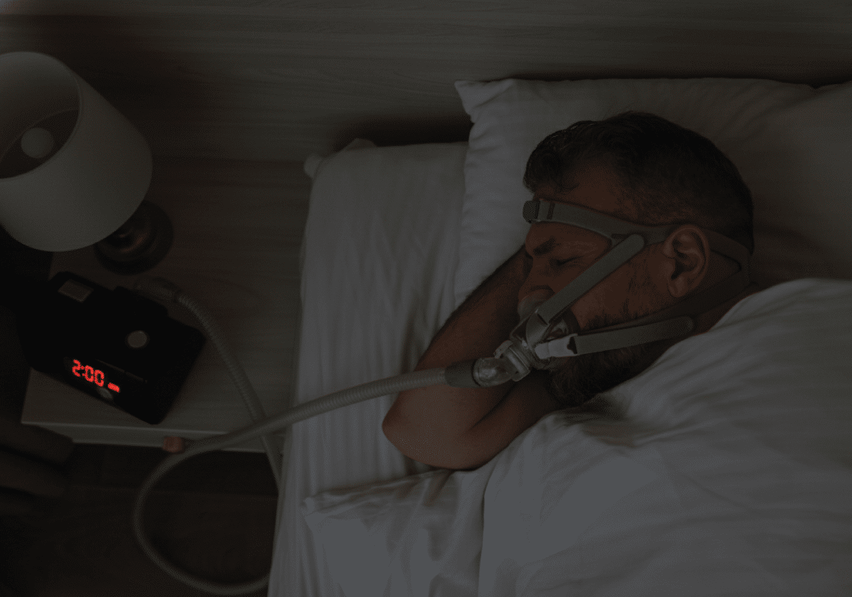 Middle-aged man sleeping soundly on his side, wearing a CPAP mask.