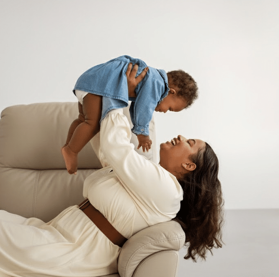 A woman playing with her child while laying across a lift chair